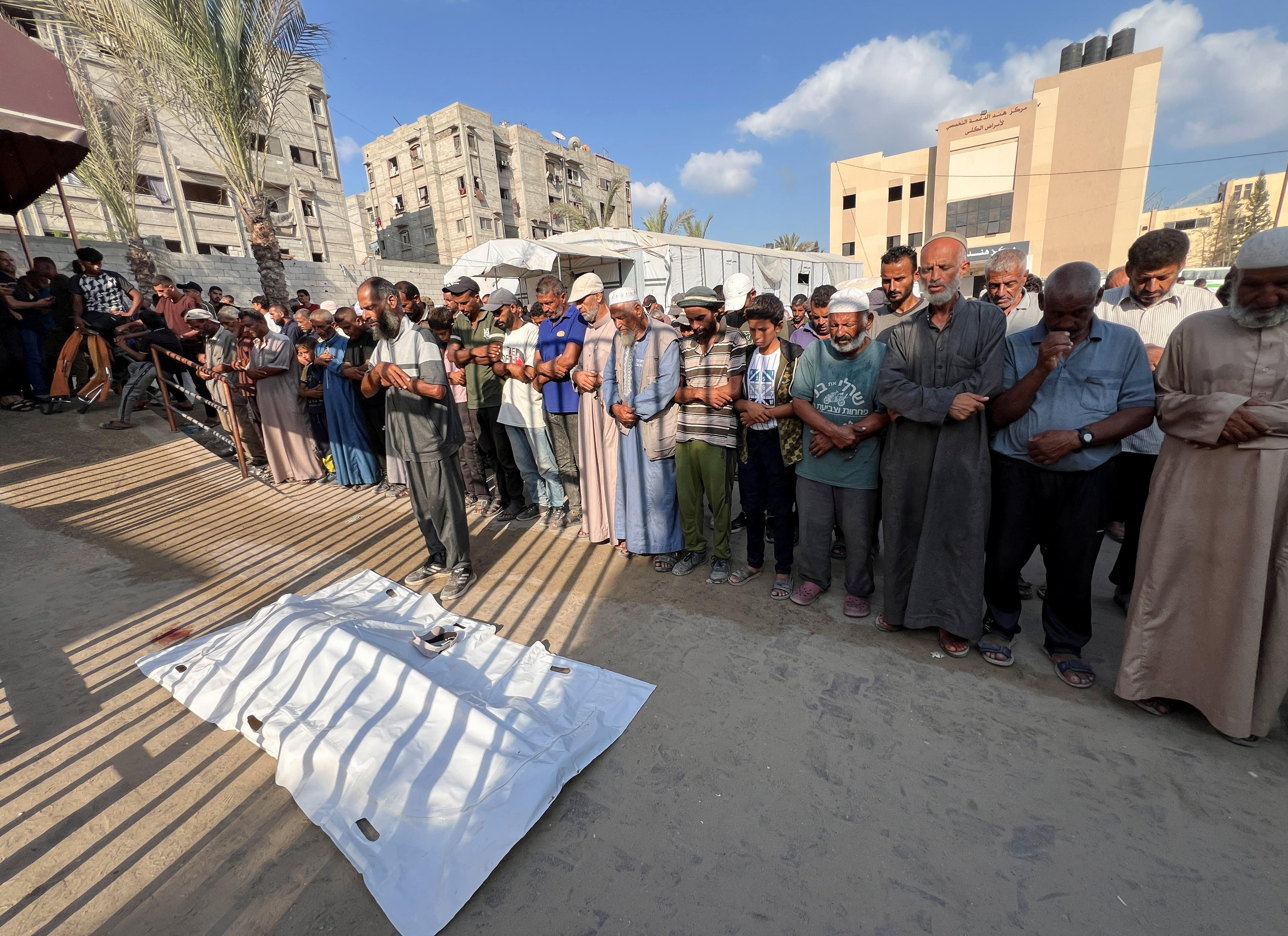 Mourners pray next to the body of a Palestinian killed by Israeli fire while seeking aid on Sunday, according to medics, at Nasser Hospital in Khan Younis, southern Gaza Strip, August 18, 2025. R