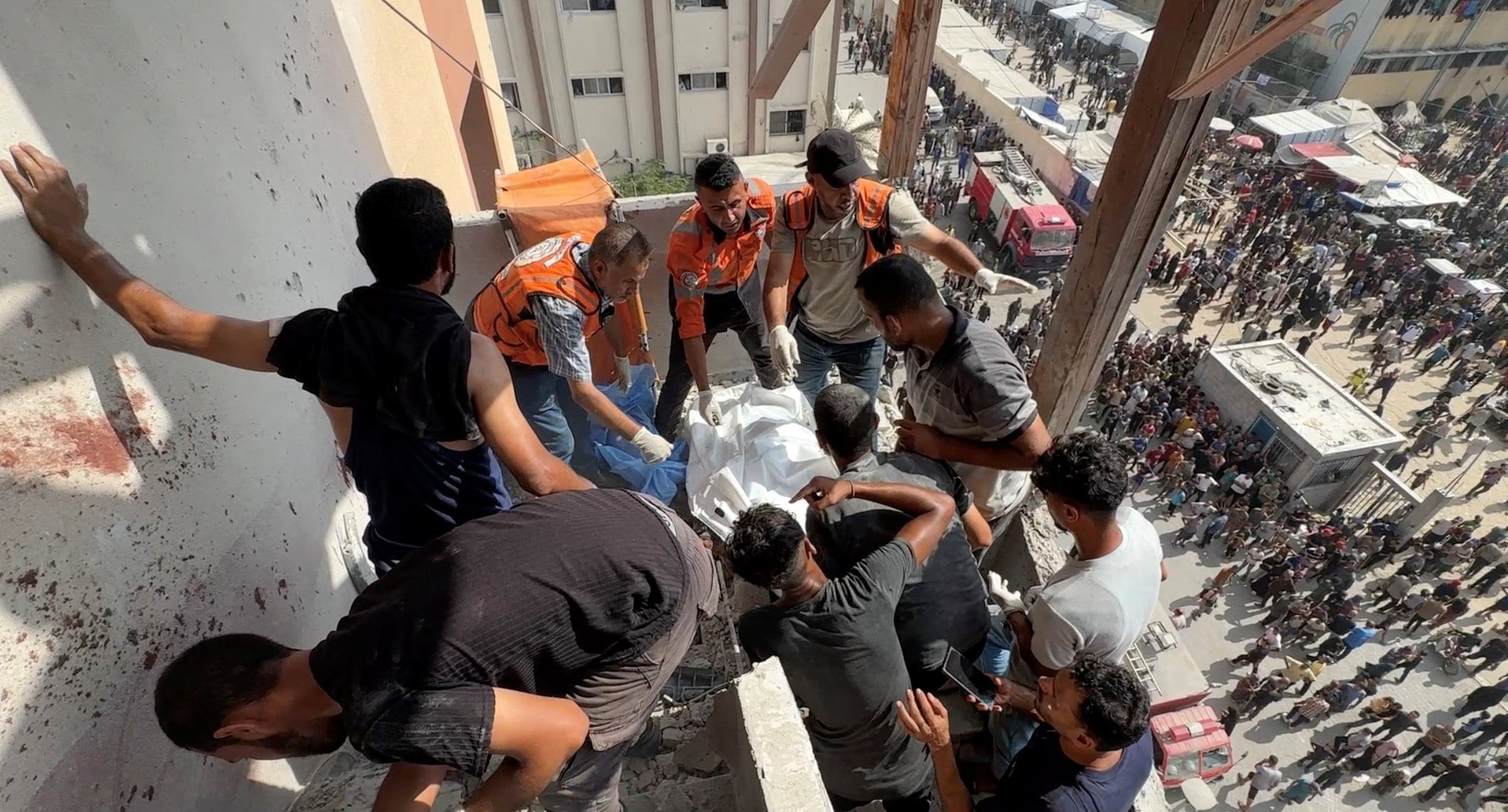 People and rescuers work to recover the body of Palestinian cameraman Hussam al-Masri, who was a contractor for Reuters, after he was killed along with other journalists and people in Israeli strikes on Nasser hospital, in Khan Younis in the southern Gaza Strip, in this still image taken from a video shot by Reuters contractor Hatem Khaled, who was wounded shortly afterwards in another strike while he was filming the site, August 25, 2025.