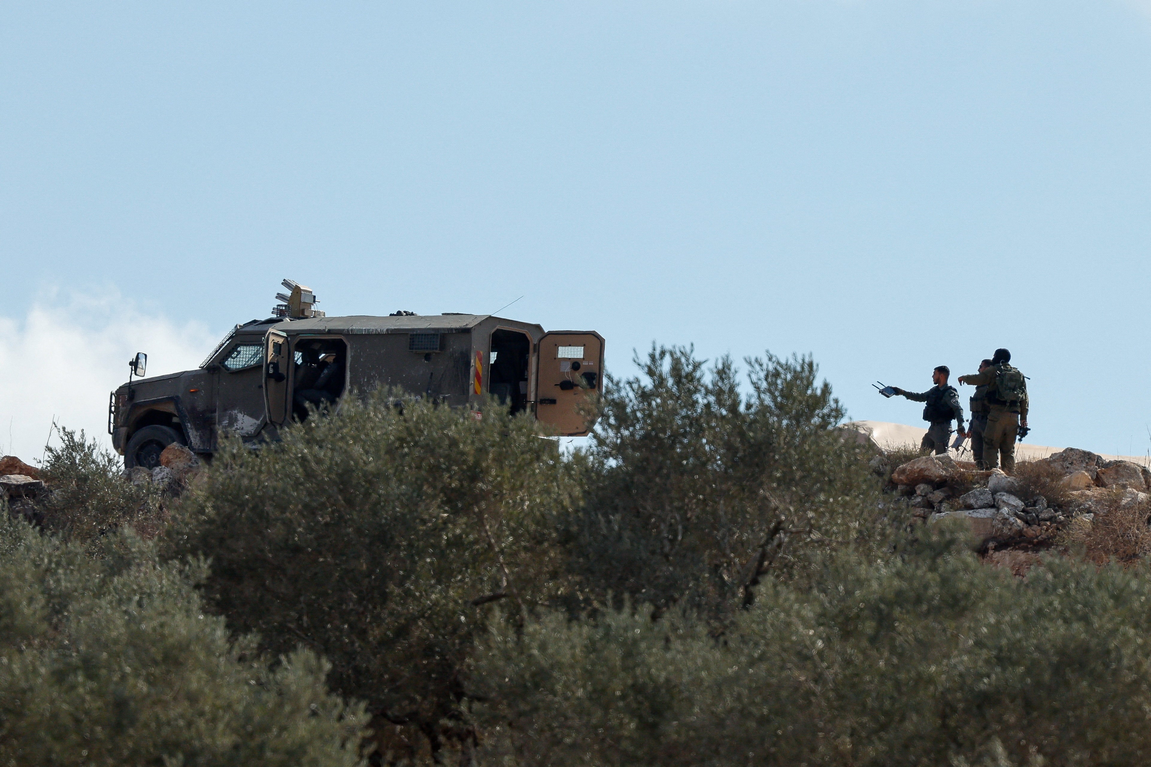 Israeli soldiers stand at the scene of the Israeli settlers' attack on olive pickers in the village of Beita, according to Palestinian media, in the Israeli-occupied West Bank, October 10, 2025.