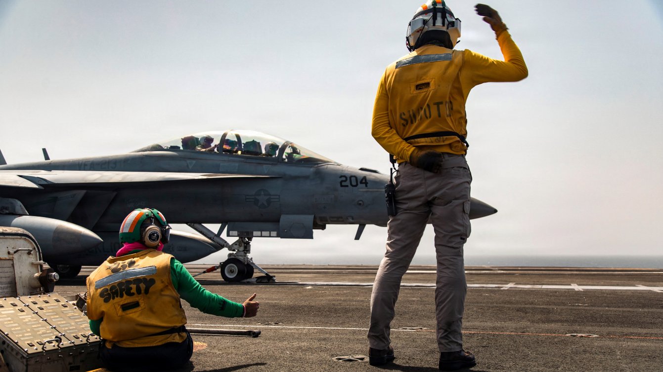 U.S. sailors signal to an F/A-18F Super Hornet aircraft, attached to Strike Fighter Squadron 213, on the flight deck of the USS Gerald R. Ford for a mission supporting Operation Epic Fury during the Iran war at an undisclosed location, March 19, 2026.