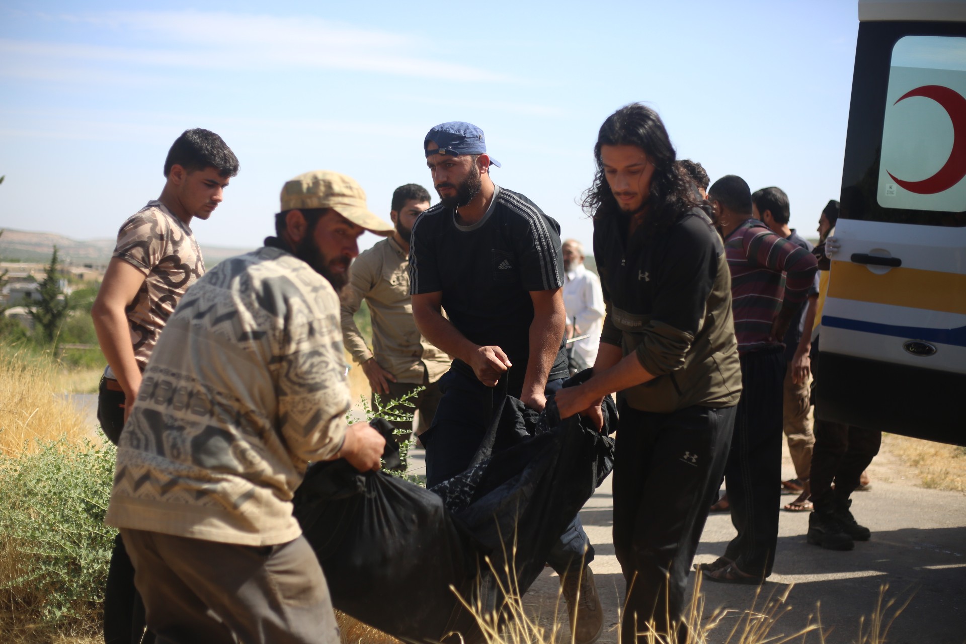 Volunteers carry the body of someone killed in a pro-Syrian government rocket attack in southern Idlib (MEE/Ali Hajj Suleiman)