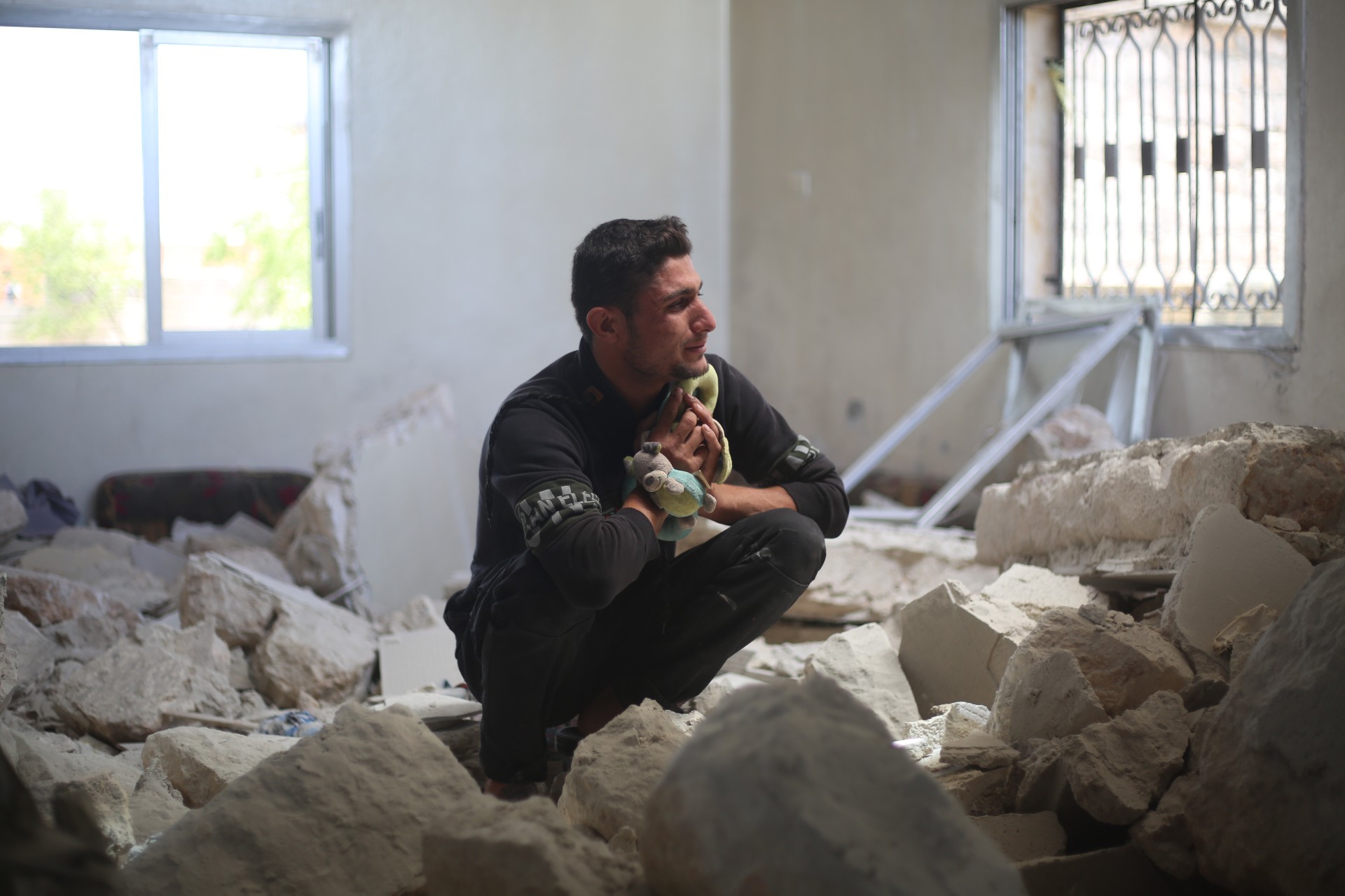 A man holding a child's toy weeps in a house in southern Idlib hit by a pro-Syrian government rocket attack (MEE/Ali Hajj Suleiman)