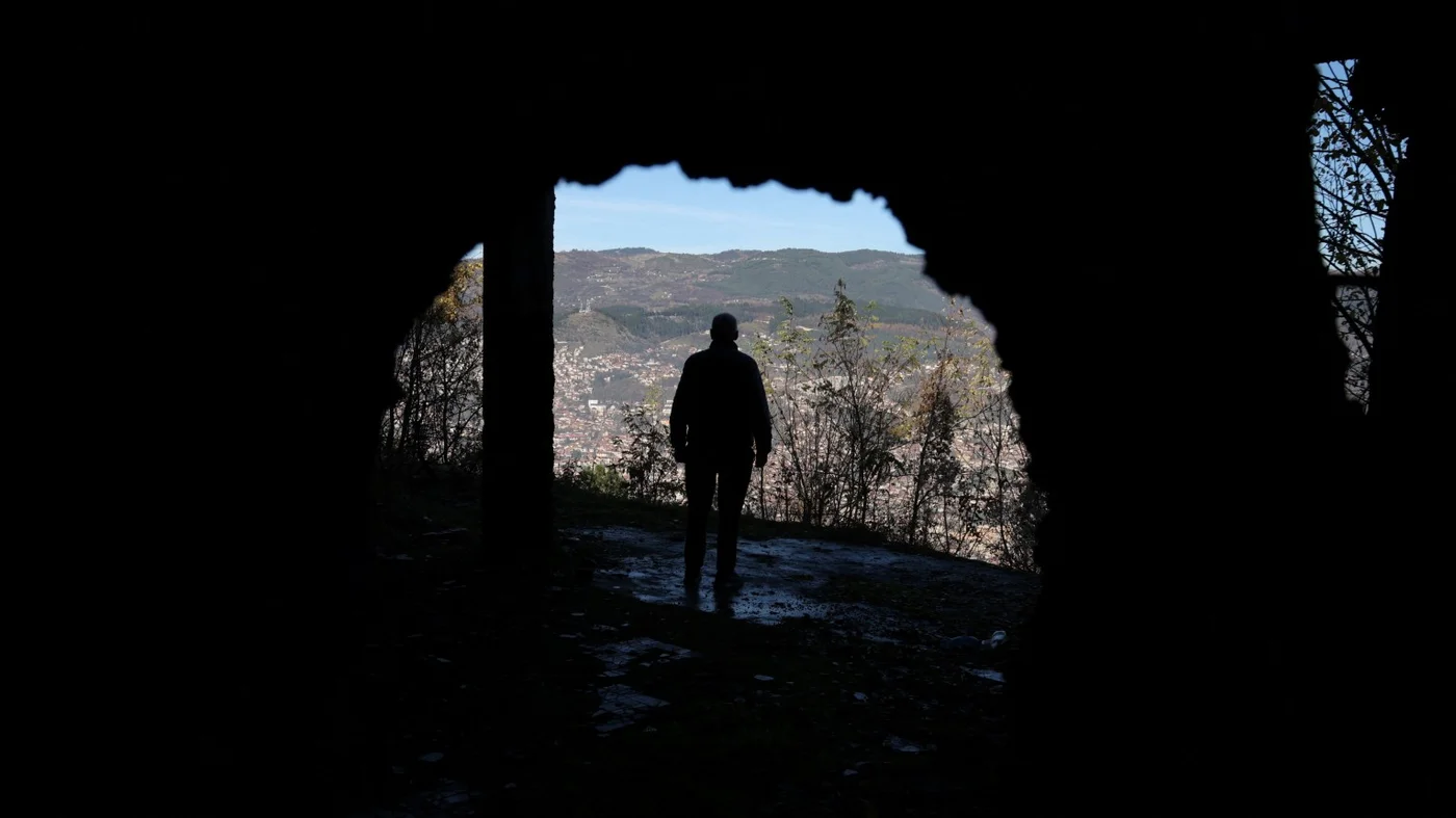 A Bosnian worker looks out at Sarajevo through a hole in a war-damaged building that once marked the front line during the 1992-95 Bosnian War in Sarajevo on 13 November, 2025 (Reuters)