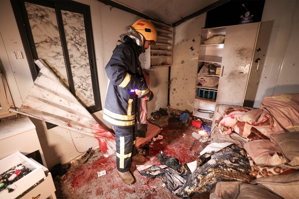 A Palestinian civil defence worker inspects the site where shrapnel from projectiles fell in Beit Awa near the Israeli-occupied West Bank city of Hebron on 18 March 2026. (AFP)