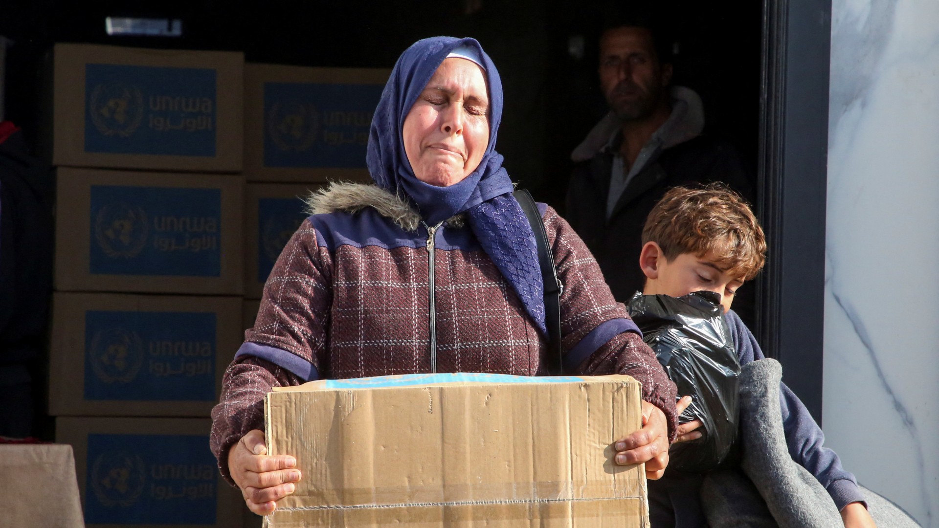 A Palestinian woman carries an aid box she received from an UNRWA distribution point, amid a ceasefire between Israel and Hamas, in Khan Younis in the southern Gaza Strip, February 4, 2025. REUTERS