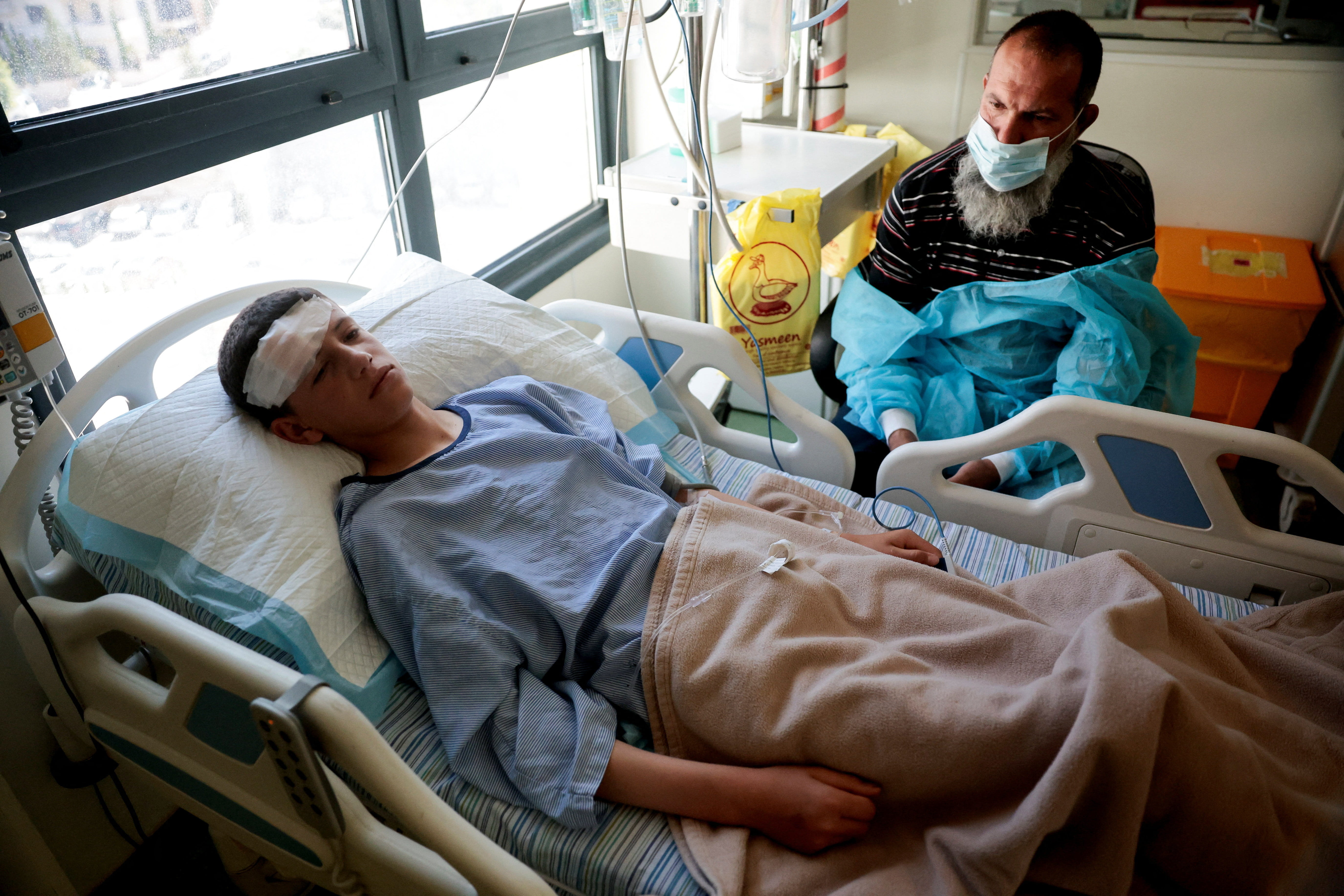 A child injured by Israeli settlers lies in a hospital bed, next to his father Youssef Muzahim, near Ramallah, in the Israeli-occupied West Bank June 2, 2026. REUTERS/Mohamad Torokman