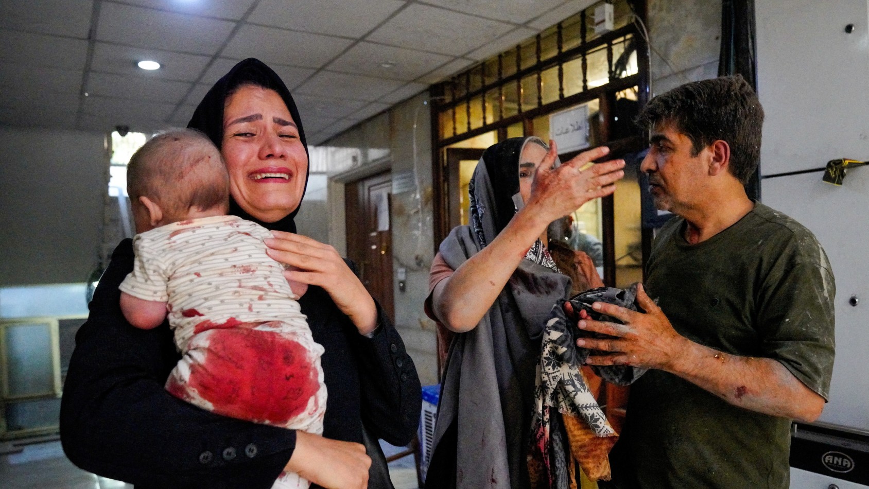 A woman carries her child following the Israeli strikes on Iran, in Tehran, Iran, June 15, 2025.