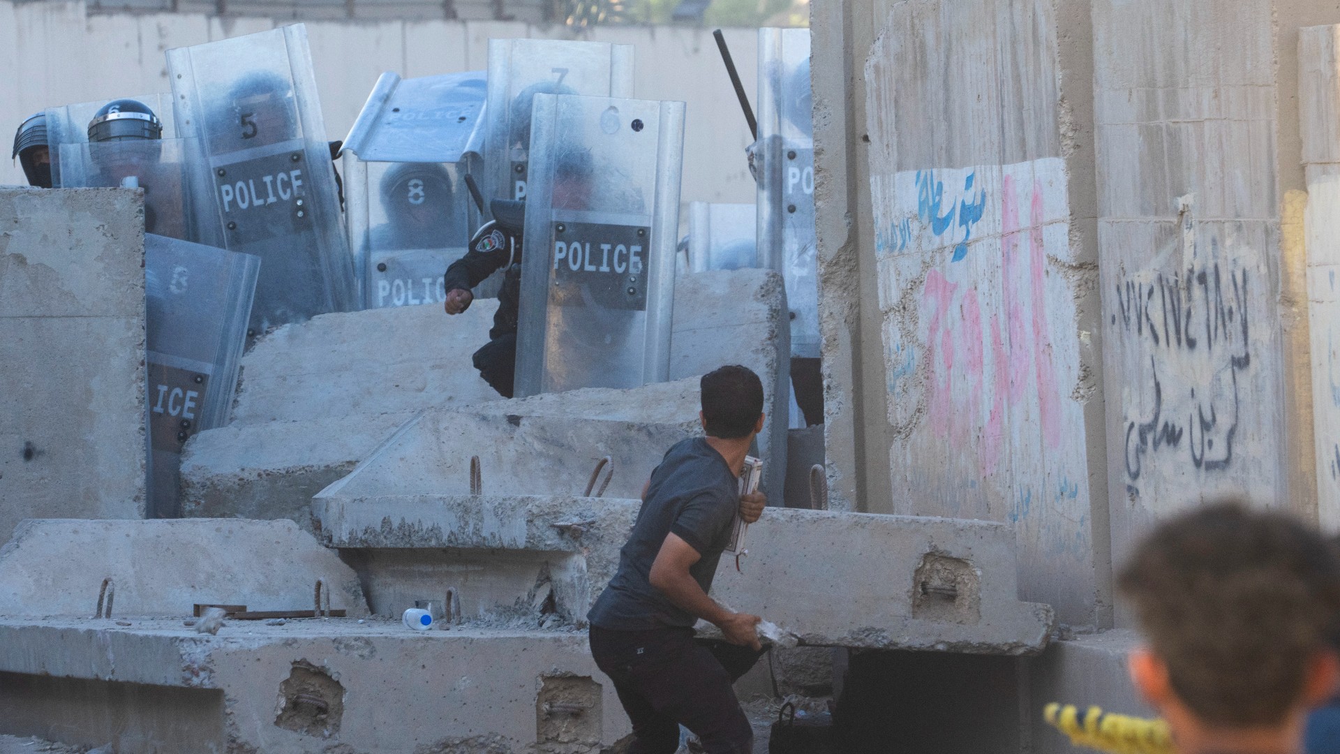 An Iraqi throws a stone during clashes with security forces in front of the Swedish embassy in Baghdad, Iraq, 20 July (AP)