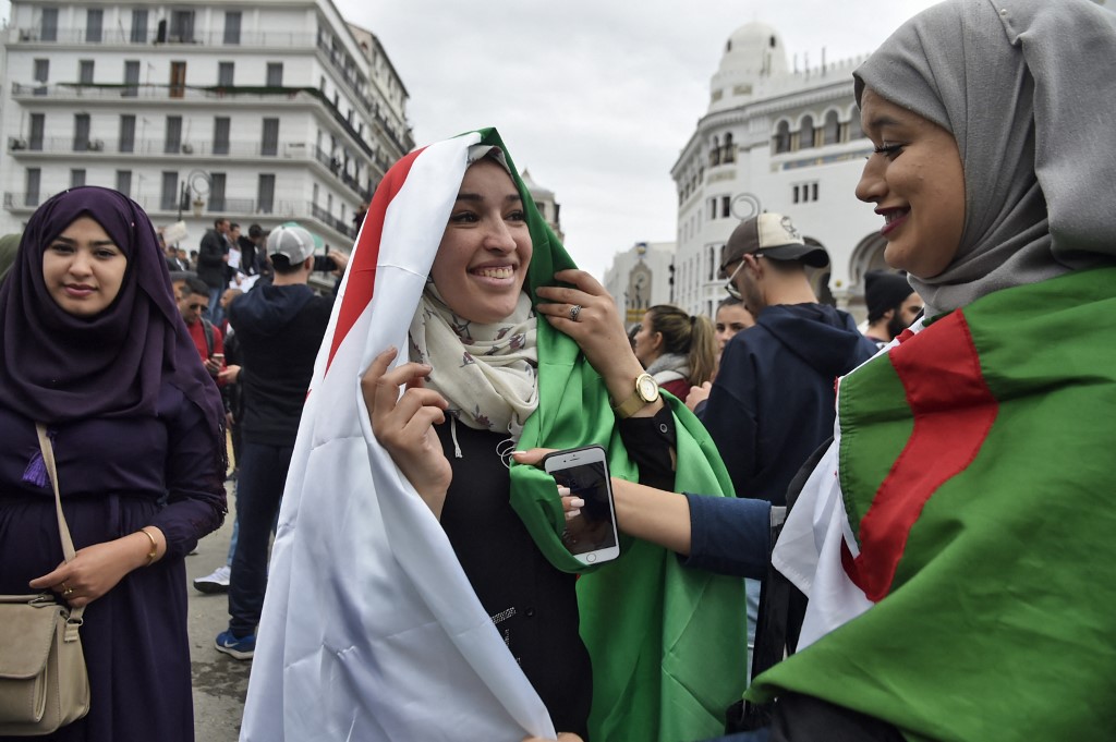 Algerian women wear their national flags as they demonstrate against president Abdelaziz Bouteflika’s bid for a fifth term in power during the so-called Hirak, in Algiers on 8 March 2019 (Ryad Kramdi/AFP)