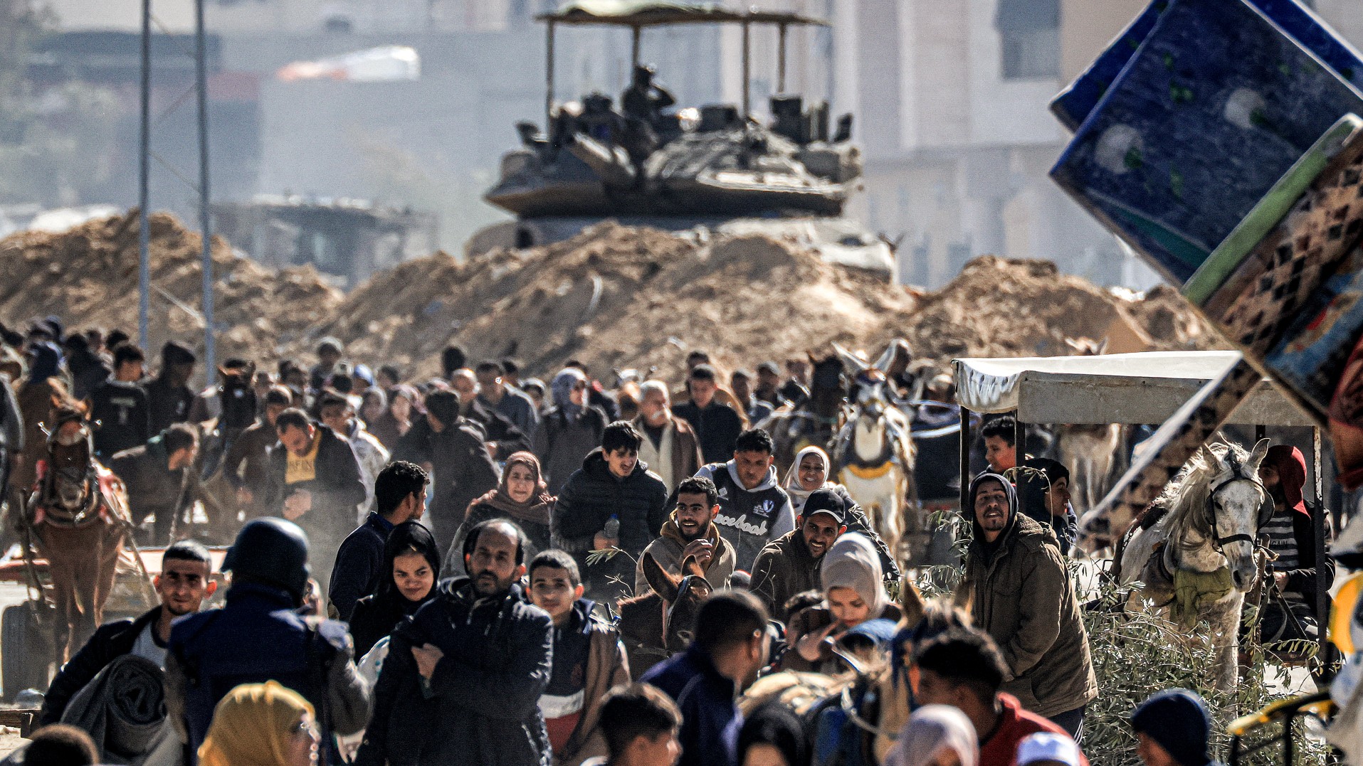 An Israeli battle tank is deployed to guard a position as displaced Palestinians flee from Khan Yunis in the southern Gaza Strip on January 30, 2024