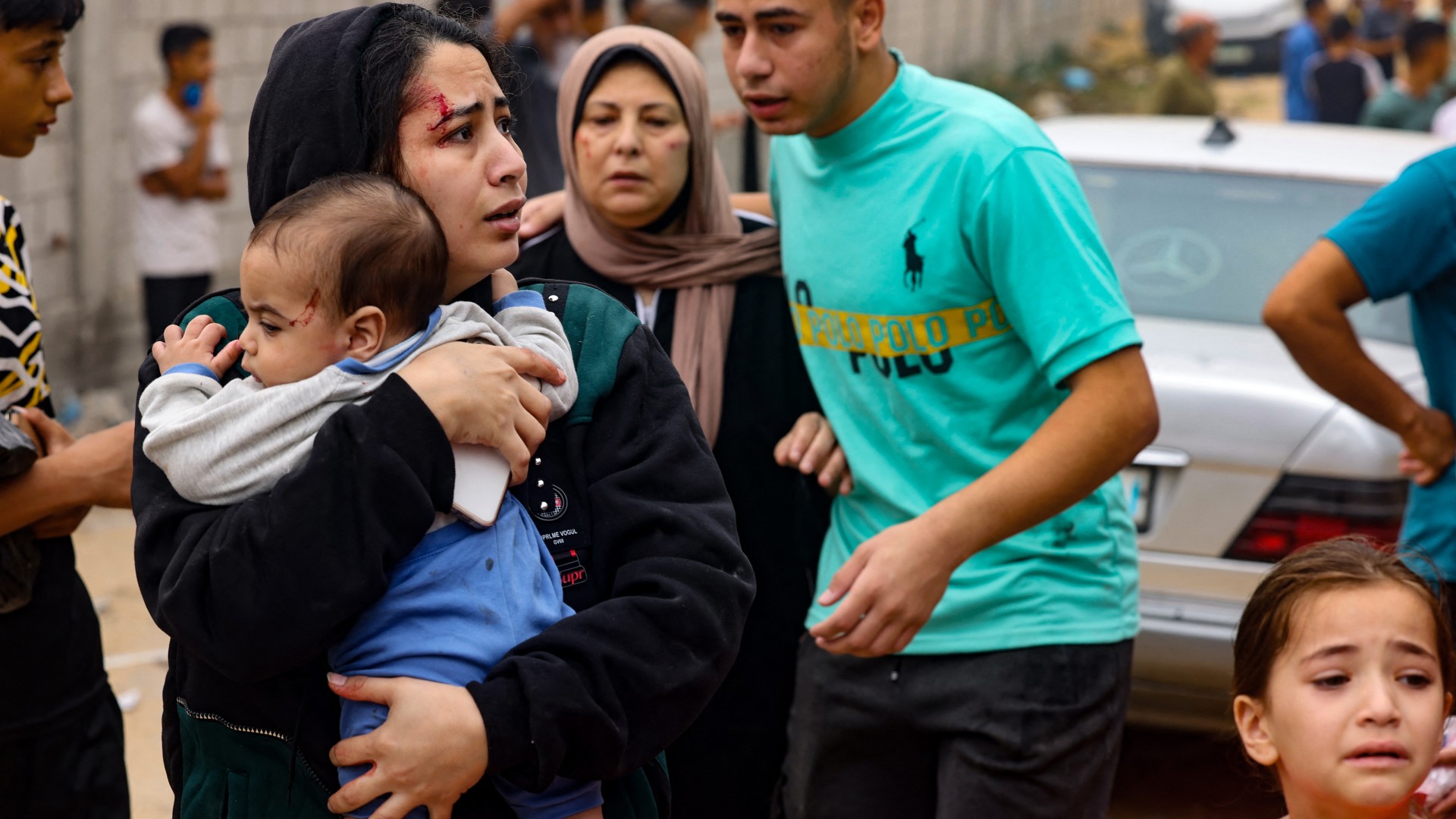 An injured woman carries a baby in the aftermath of Israeli bombing in Rafah in the southern Gaza Strip on October 29, 2023.