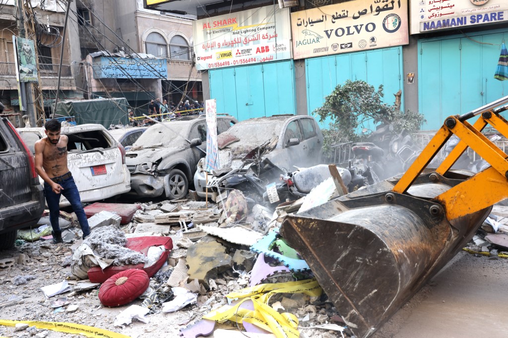 A machine clears debris in a street under a residential building whose top two floors were hit by an Israeli strike in the Ghobeiri area of Beirut's southern suburbs on September 24, 2024 (AFP)