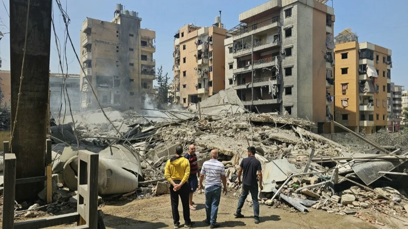 Men stand before the rubble of a collapsed building at the site of an overnight Israeli air strike in the Kafaat neighbourhood of Beirut’s southern suburbs on 6 June 2025 (AFP)