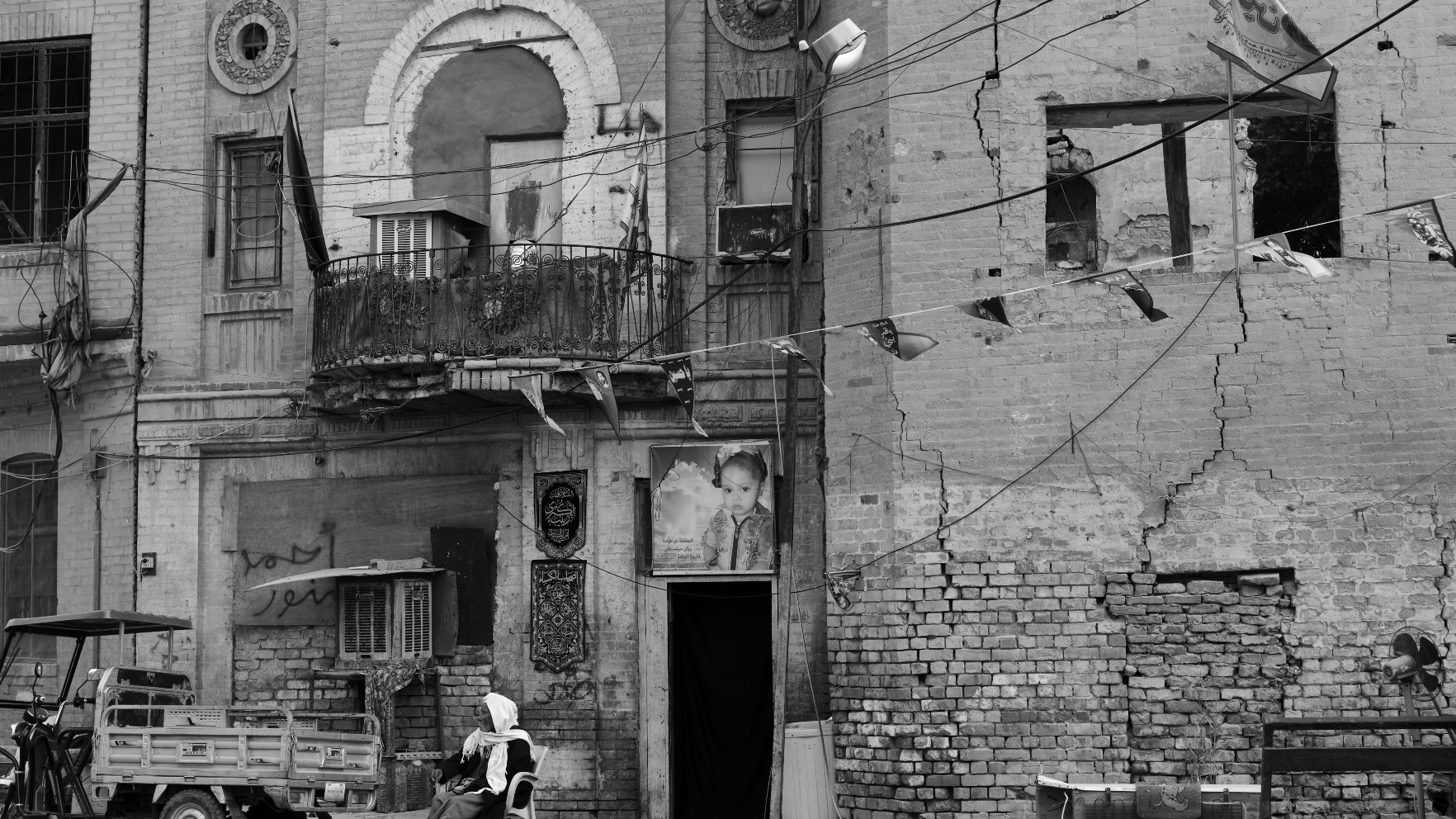An Iraqi man outside a rundown house with a dead child's portrait in Baghdad in November 2020 (Nabil Salih)