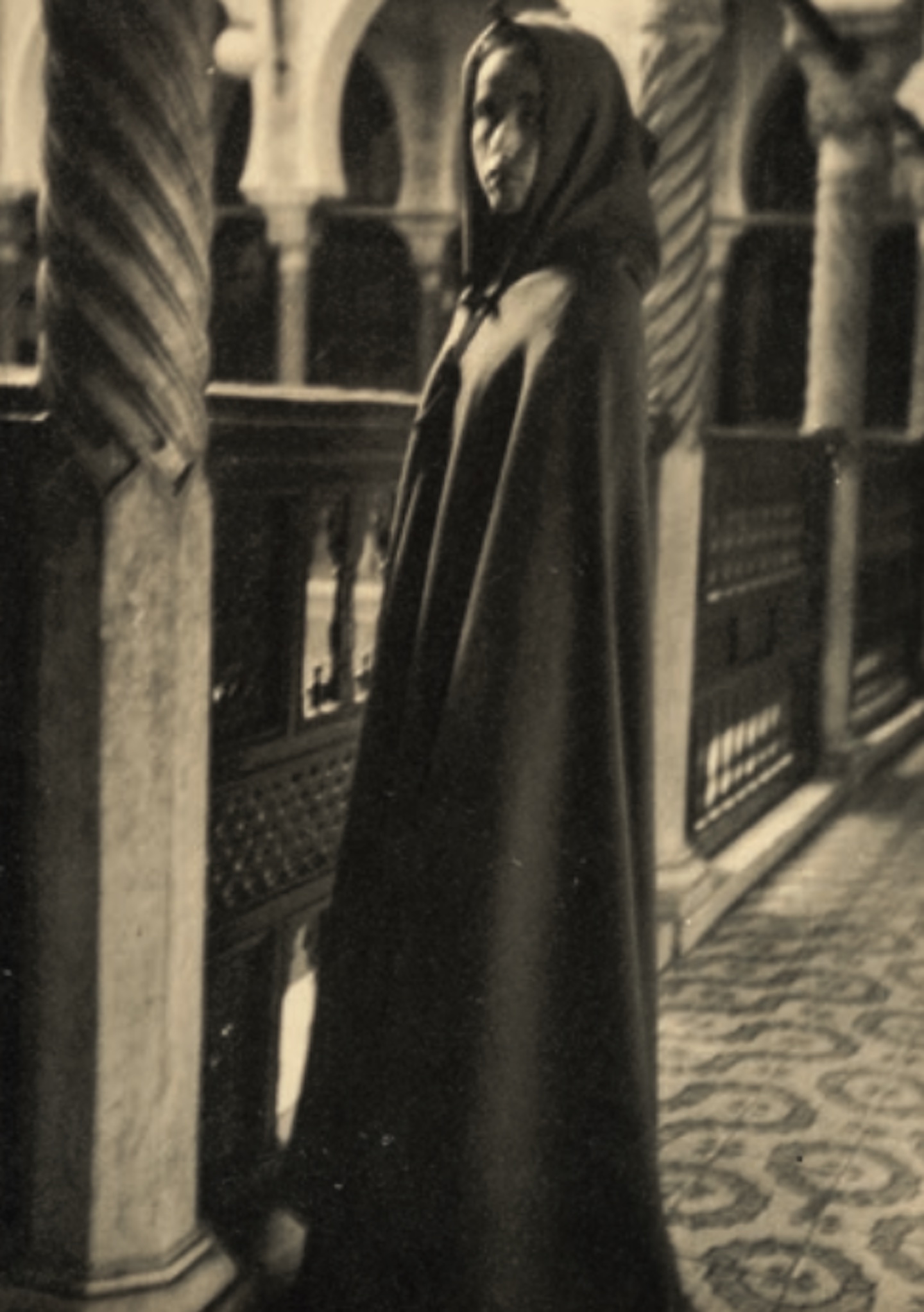 Baya en burnous au Palais d’Hiver (Dar Hassan Pacha), Alger, 1947. Tirage monochrome sur papier chamois, annotations à l’encre noire au verso, 23,4 x 17,5 cm. (Aix-en-Provence, Archives nationales d’outre-mer, France)