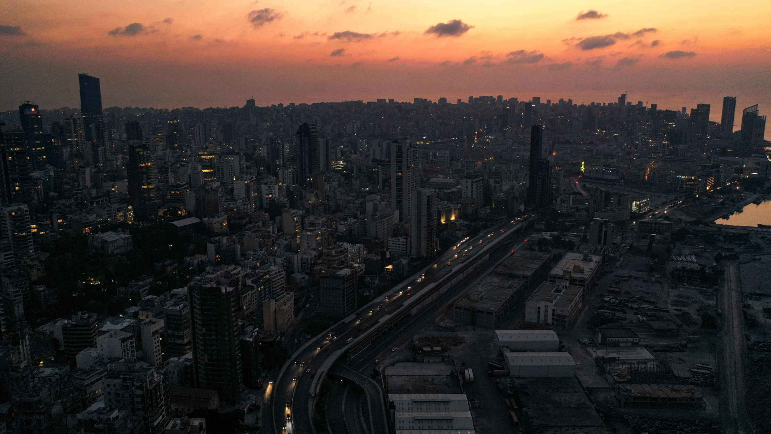 Adusk aerial view of cars driving past unlit buildings along the Charles Helou highway n darkness during a power outage (AFP)