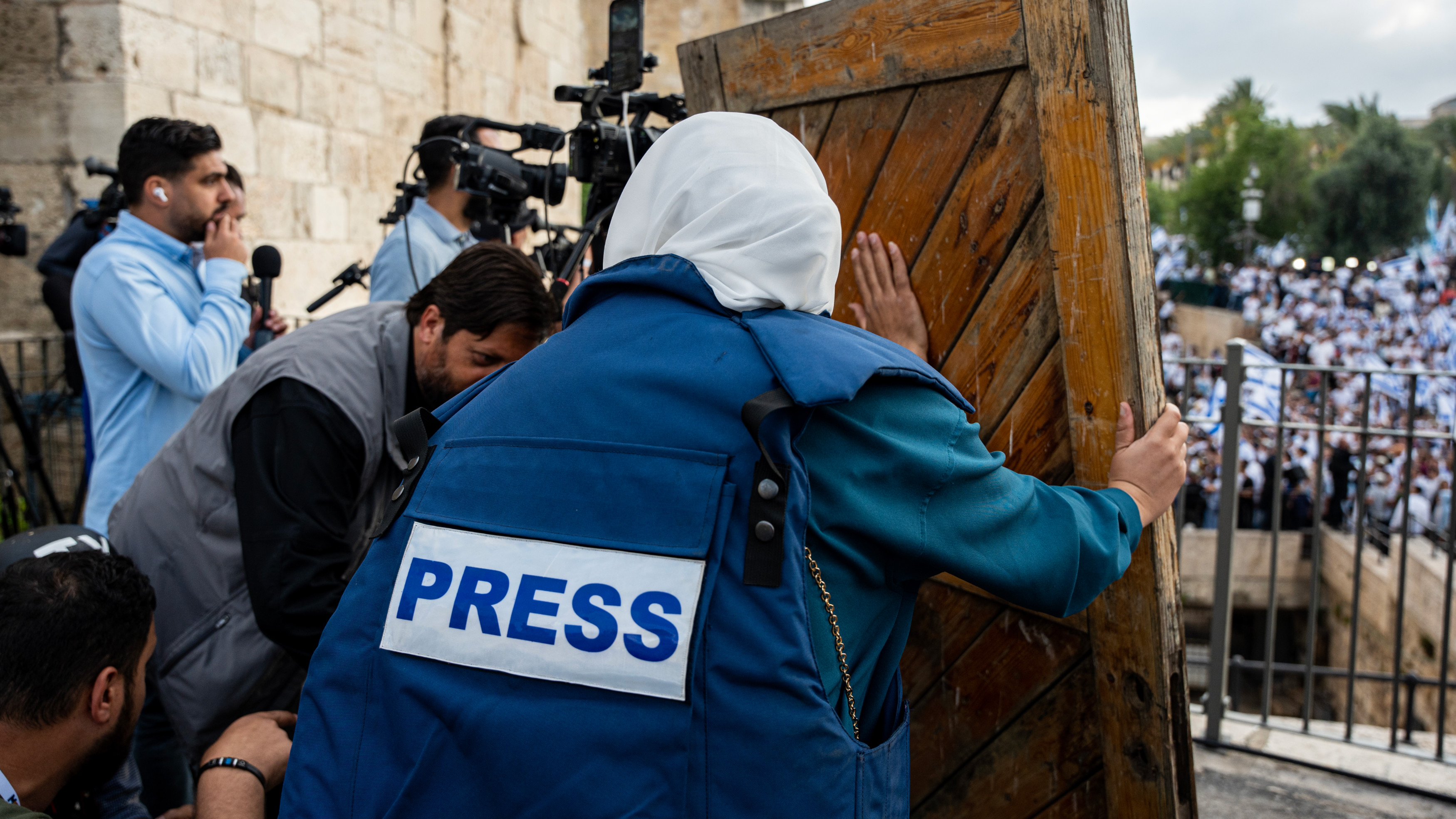Journalists take cover as Israeli crowds throw projectiles at them while chanting racists slogans during the 