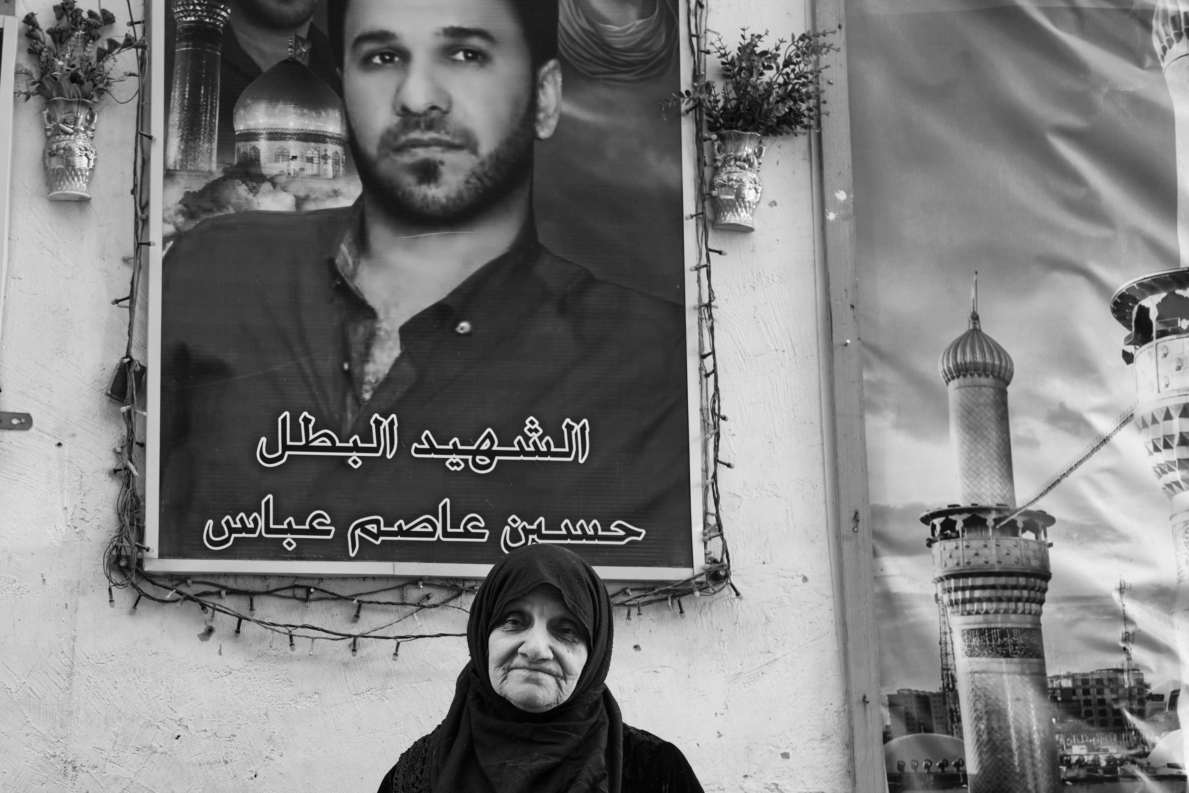 An Iraqi woman standing next to her maryred son's portrait in Baghdad on 25 February, 2021 (Photo by Nabil Salih) 