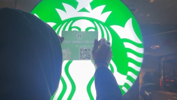 An activist places one of the fake promotional stickers on a Starbucks location.