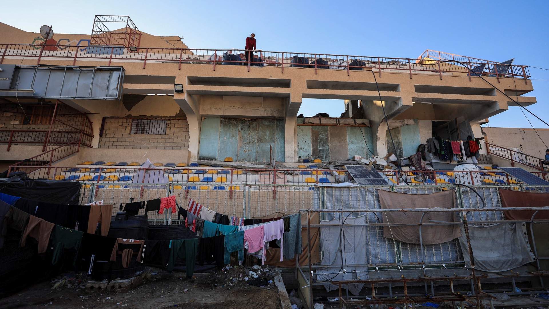 A Palestinian man stands atop a building at Palestine Stadium, which was damaged during the Israeli offensive, where displaced people take shelter, in Gaza City, March 11, 2025. REUTERS/Dawoud Abu Alkas