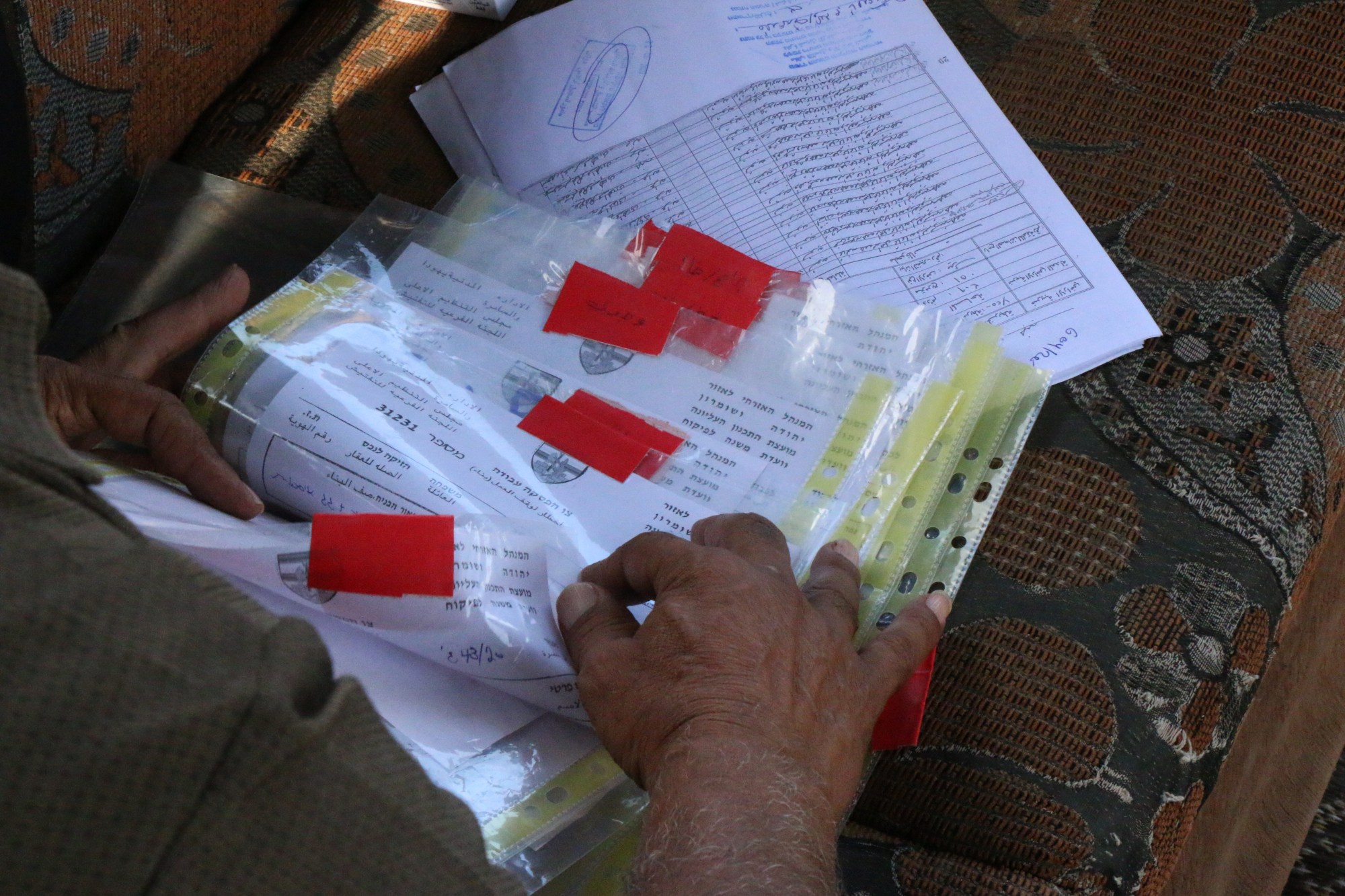 Mahmoud Amarneh flips through all the orders handed down by Israeli authorities to the village of Farasin (MEE/Akram al-Waara)