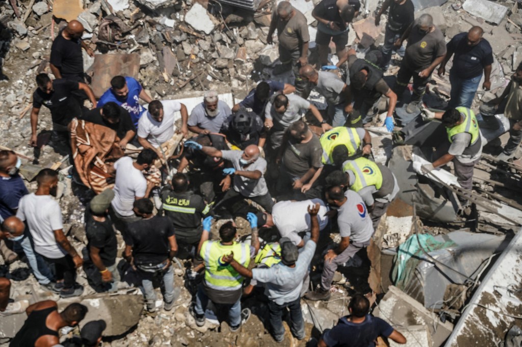 First aid responders and residents gather as they search the site of an Israeli airstrike that targeted a neighbourhood in the southern Lebanese village of Deir al-Zahrani on 15 August 2026 (AFP)
