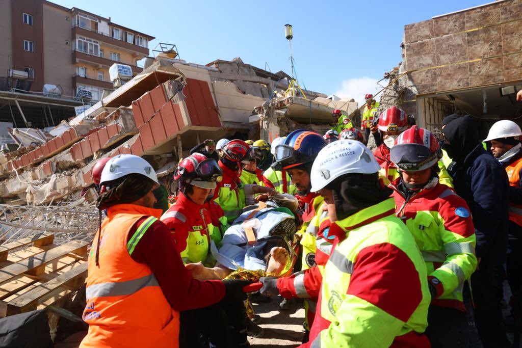 Members of the German International Search and Rescue (ISAR) pull a woman from the rubble of a house on 10 February, 100 hours after the quake (Twitter: ISAR)