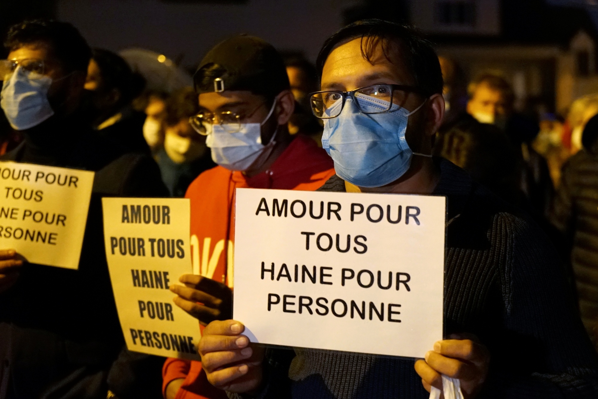 People attend a silent march to pay tribute to Samuel Paty in Conflans-Sainte-Honorine, France, on 20 October 2020. The slogan reads 