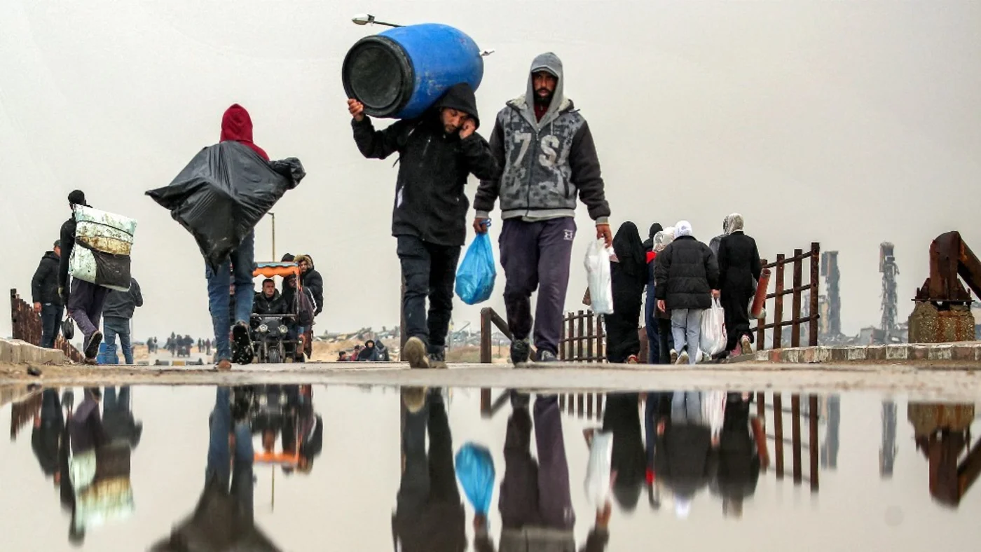 People walk with belongings along the Wadi Gaza bridge along al-Rashid street across between Gaza City and Nuseirat in the central Gaza Strip on February 10, 2025 as displaced people return home amid the current ceasefire deal in the war between Israel and Hamas (Eyad Baba / AFP)
