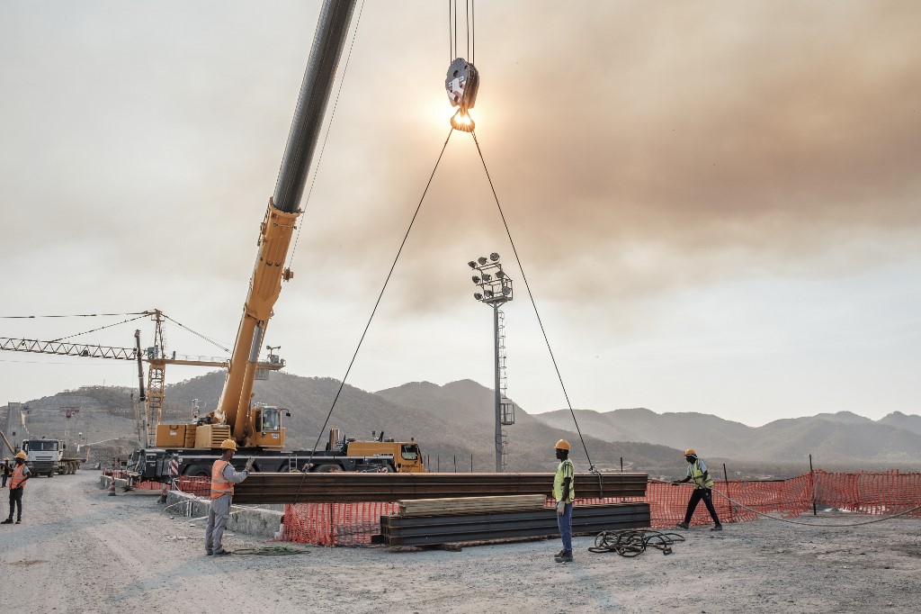 Workers move iron girders from a crane at the GERD on 26 December (AFP)