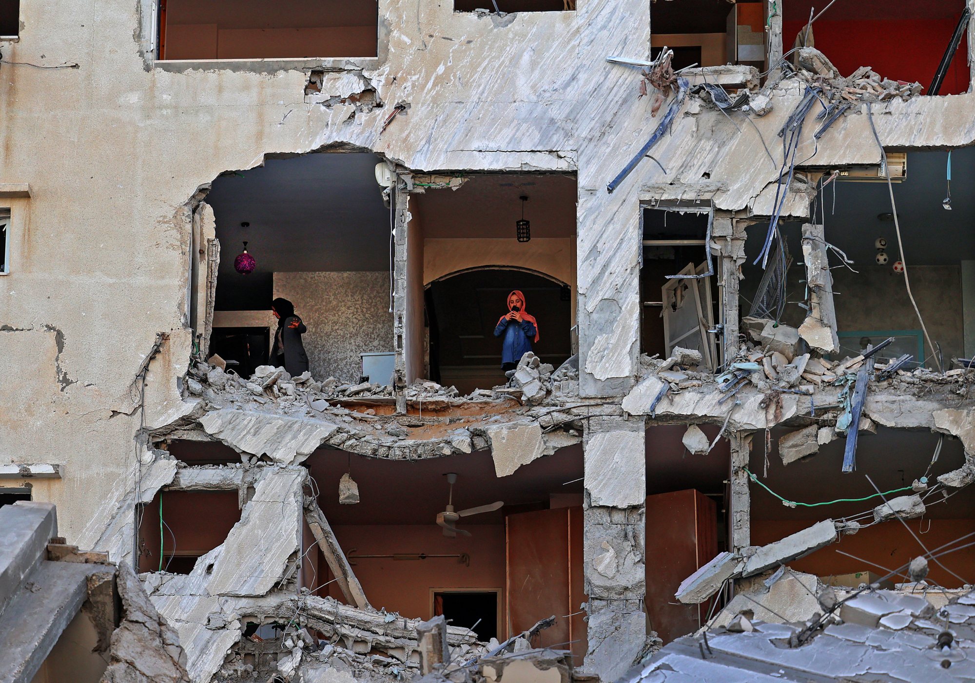 Palestinian women check the damage inside an apartment in a heavily damaged building in Gaza City early on 12 May 2021 (AFP/ Mohammed Abed)