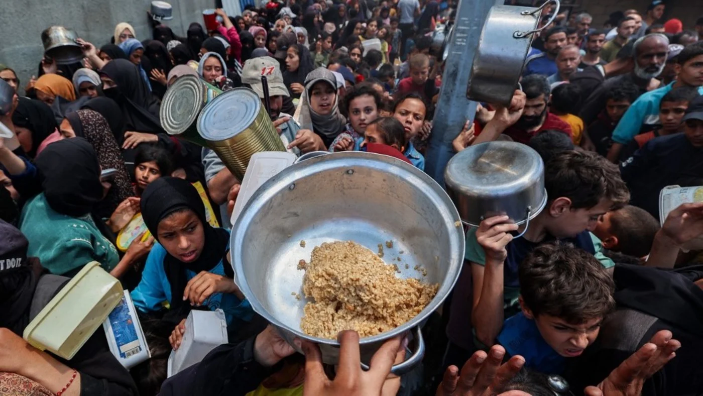 Palestinians gather at a food distribution point in the Nuseirat camp for refugees in the central Gaza Strip on 21 May 2025 as Israel allowed a limited amount of aid into the enclave (Eyad Baba/AFP)