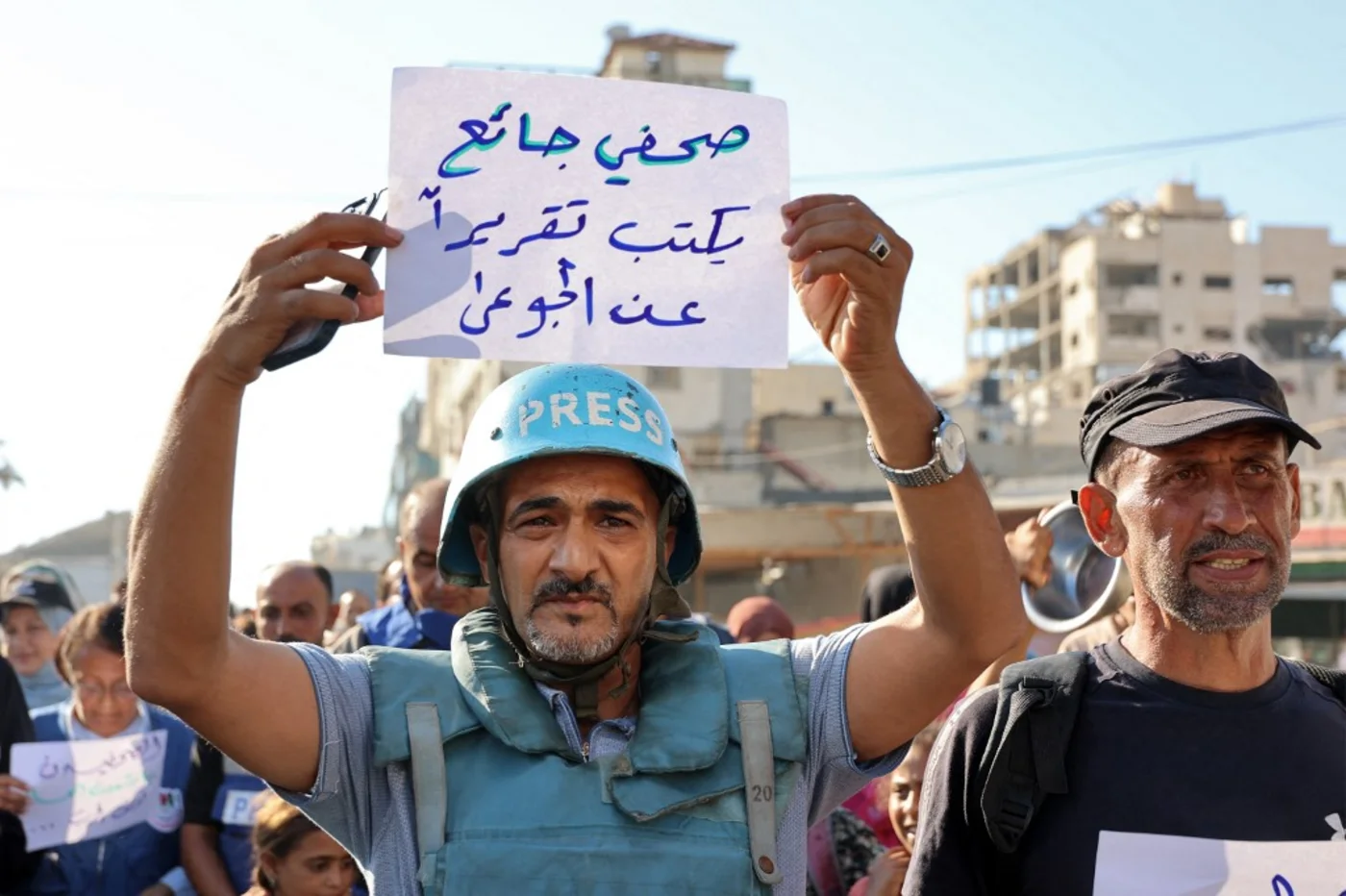 A demonstrator holds a sign in Arabic that reads 'a hungry journalist writes a report about the hungry' in Gaza City on 19 July (AFP/Omar al-Qattaa)
