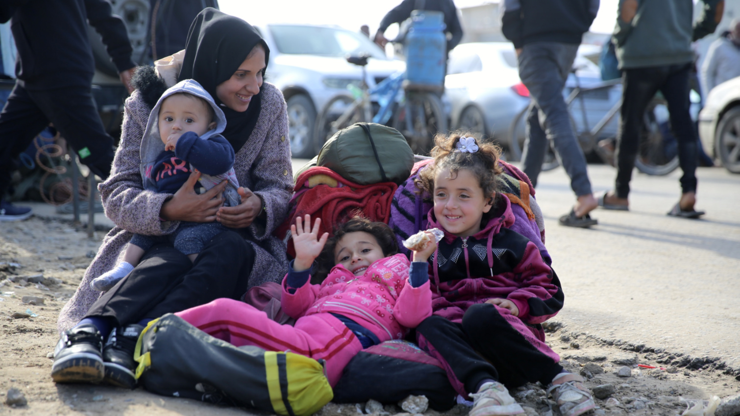 A woman and three children shit near the Netzarim corridor, waiting to be allowed back north on 25 January 2025 (Mohammed al-Hajjar/MEE)