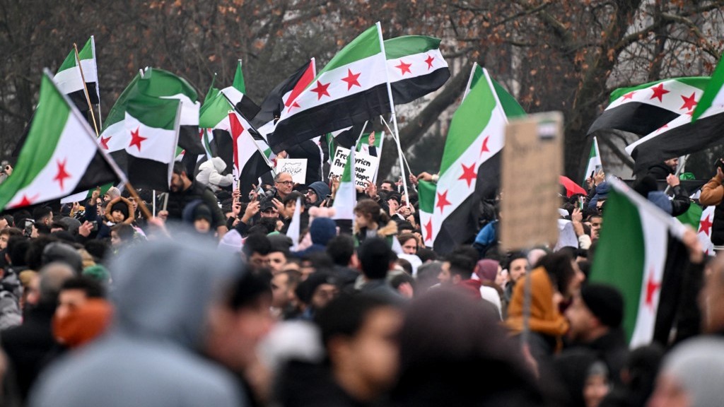 Members of the Syrian community wave Syrian flags on December 8, 2024 in Berlin, Germany, and celebrate the end of Syrian dictator Bashar al-Assad's rule after rebel fighters took control of the Syrian capital Damascus overnight. 
