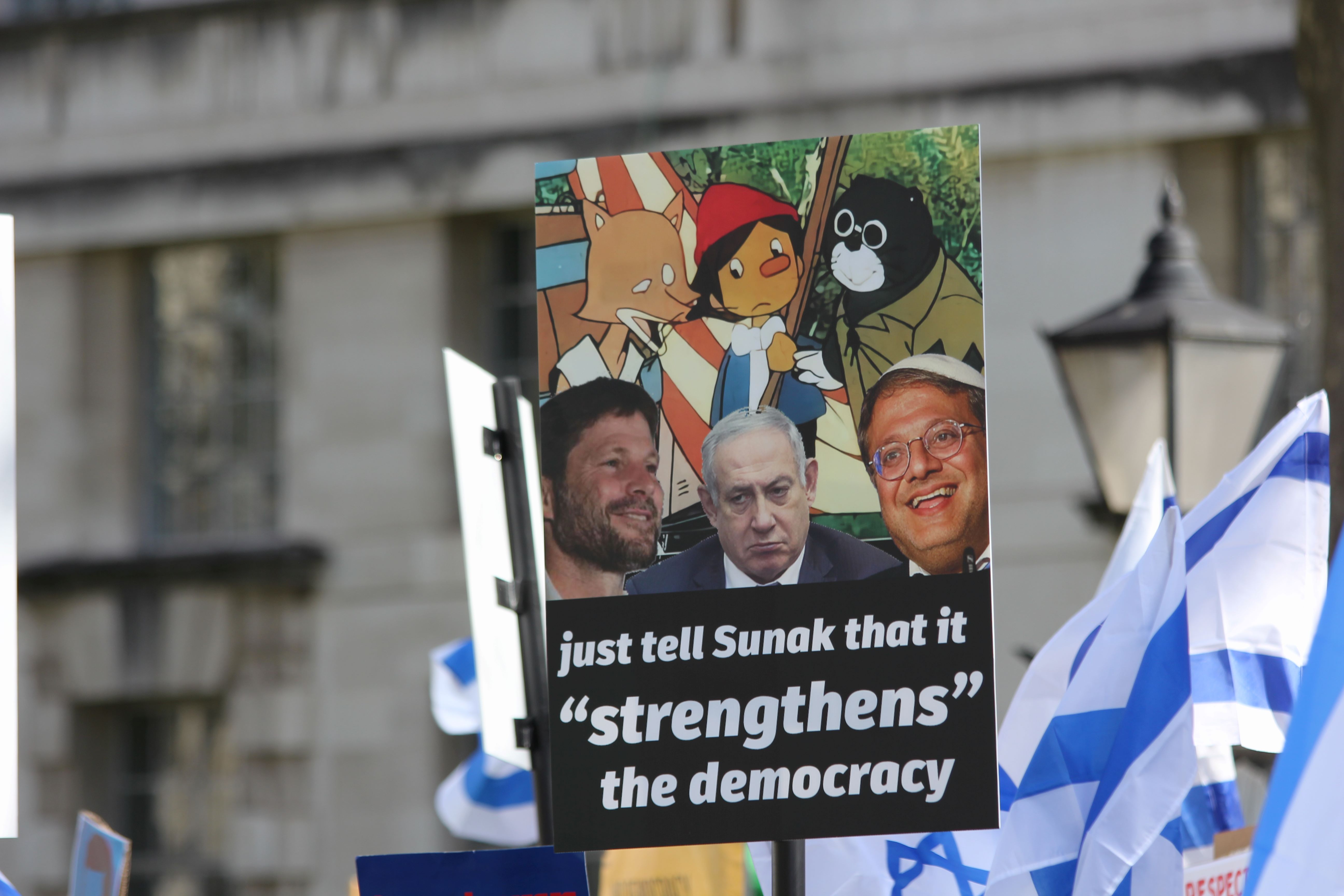 A demonstrator holds a placard depicting Netanyahu and far-right minister Bezalel Smotrich and Itamar Ben-Gvir (MEE/Alex MacDonald)