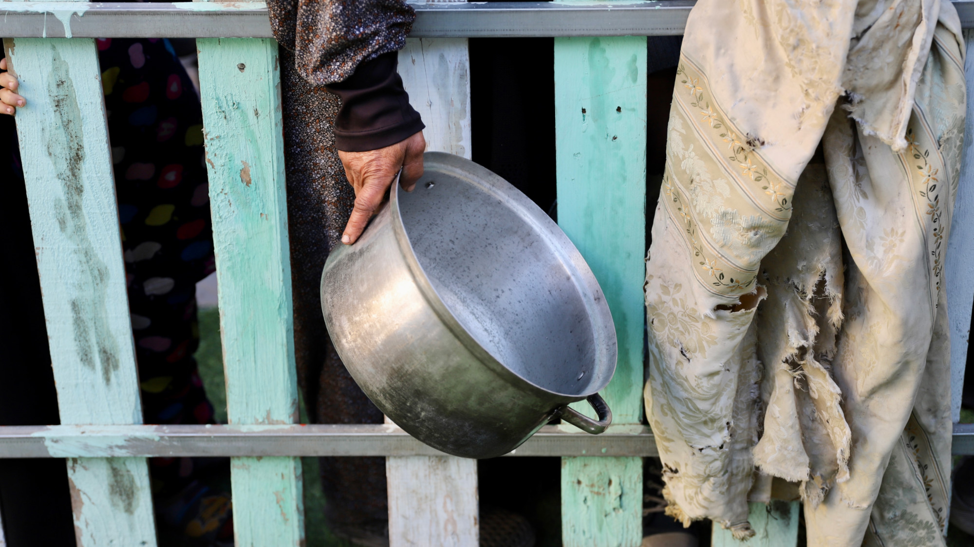 A Palestinian woman carries and empty pot at a food distribution point in Gaza City (MEE/Mohammed al-Hajjar)