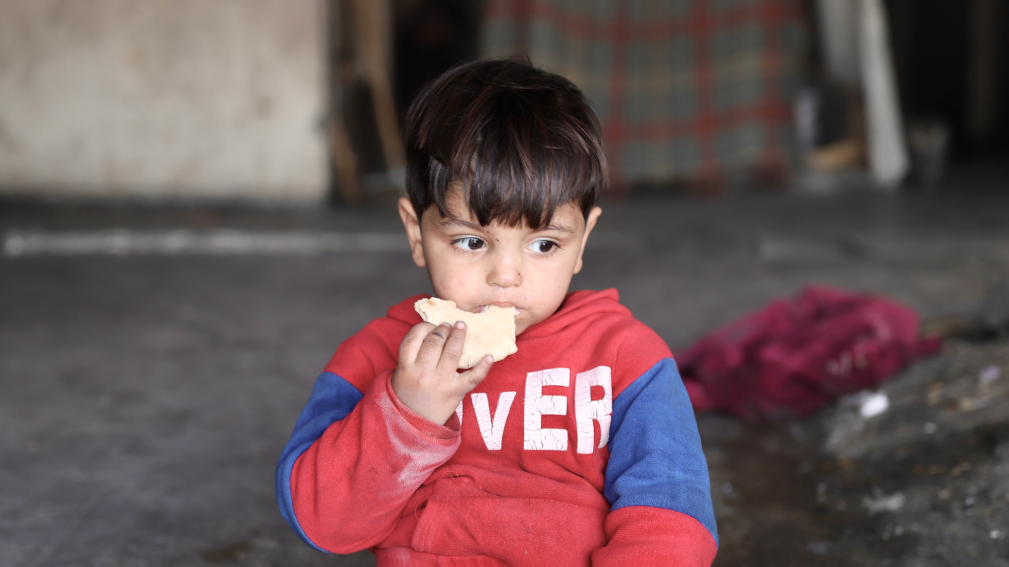 A Palestinian child eats a load of bread in Gaza City (MEE/Mohammed al-Hajjar)