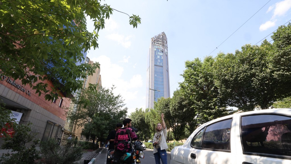 Onlookers gather in front of a building damaged in an Israeli strike on Tehran on June 13, 2025 (AFP)