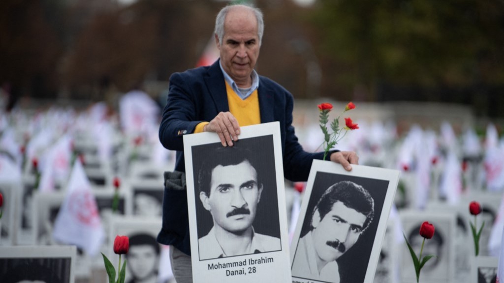 A member of the People's Mujahedin of Iran in France displays portraits of victims of the 1988 executions in 2019 (Eric Feferberg / AFP)