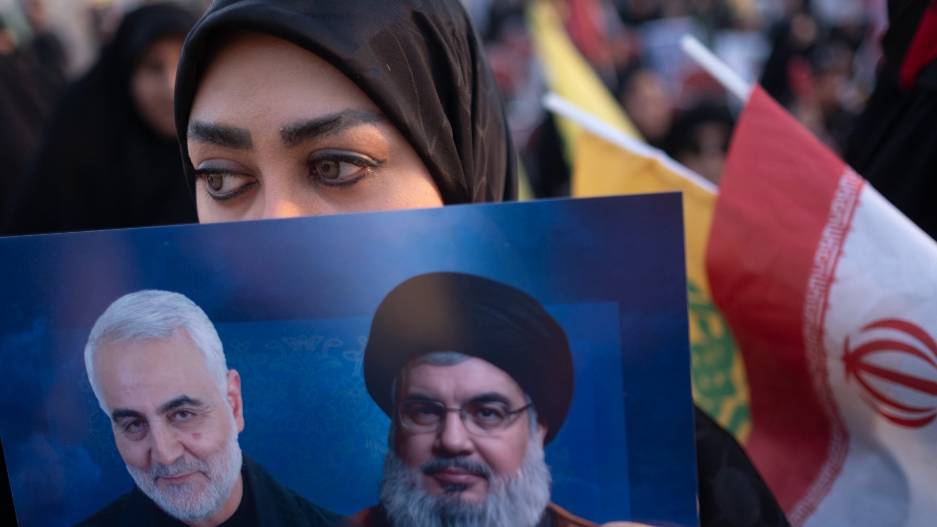 A woman holds a poster depicting Qassem Soleimani and Hassan Nasrallah during a commemoration of Nasrallah's death in southern Tehran on 2 October 2025 (Morteza Nikoubazl/NurPhoto/Reuters)