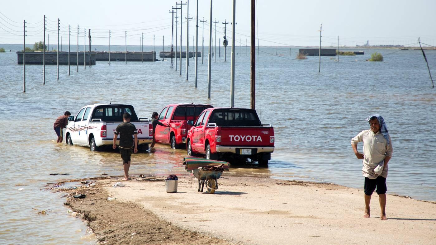 Des véhicules au bord d’une zone inondée dans le district d’al-Qurnah, au nord de Bassorah dans le sud de l’Irak, en avril 2019 (AFP)