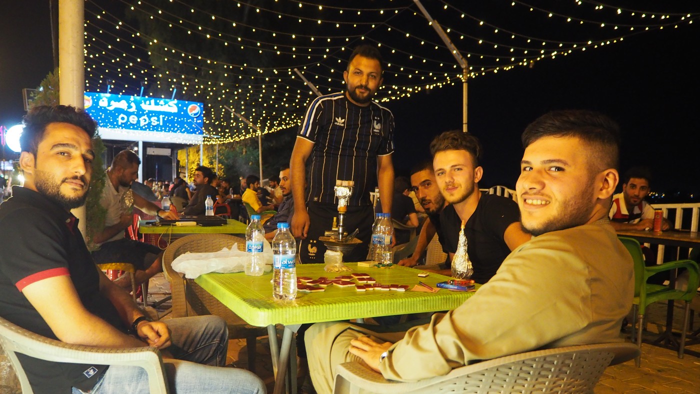 Young Mosulis smokE shisha and play dominoes on Mosul's Jungle Street, in the city's al-Gharbaat district (MEE/)