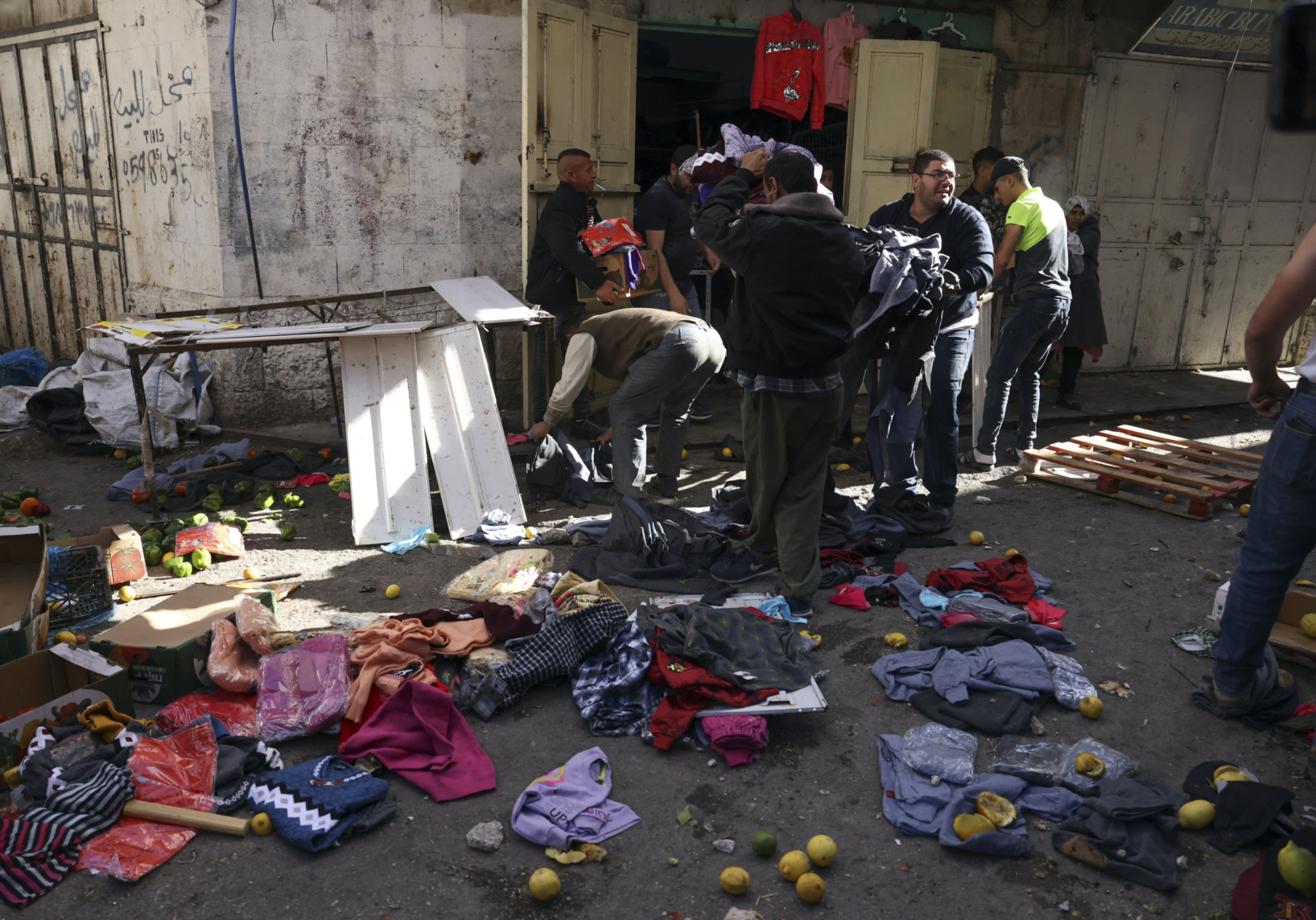 Palestinian shop owners salvage their merchandise at a market, ransacked by marching Jewish settlers in Hebron (AFP)