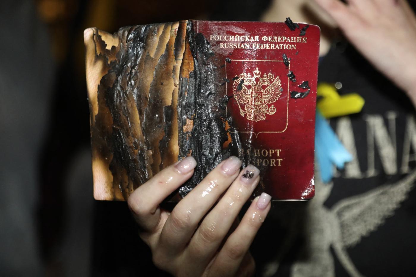 A woman holds her Russian passport after burning it during a demonstration outside the Russian embassy in Tel Aviv on 24 February 2022.