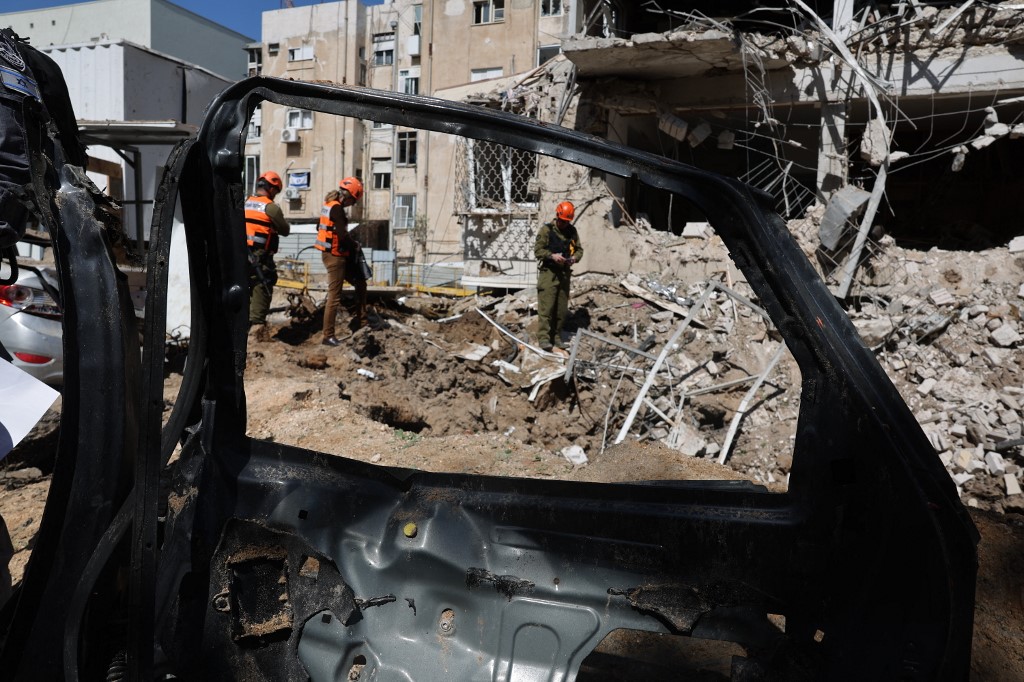 Israeli emergency service personnel gather at the site of an Iranian missile strike in Tel Aviv on 24 March, 2026. (AFP)