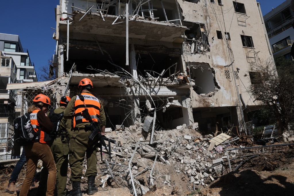 Israeli emergency service personnel gather at the site of an Iranian missile strike in Tel Aviv on 24 March, 2026. (AFP)
