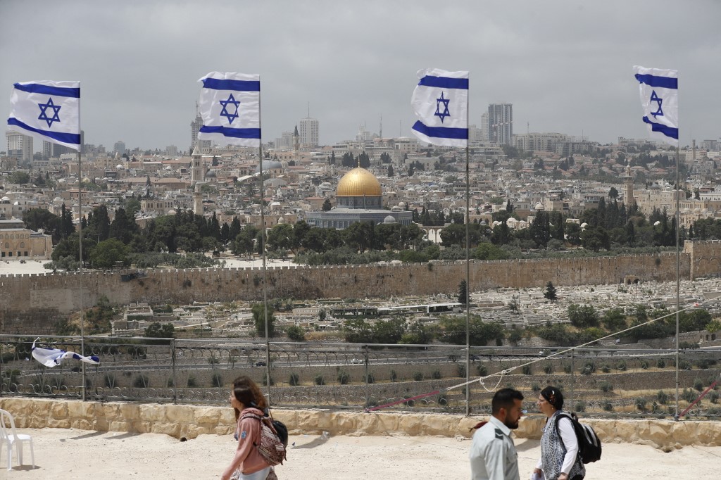 Israeli flags flutter at the military cemetery on the Mount of Olives, overlooking the Dome of the Rock mosque (background), in Jerusalem, 4 May 2022 (AFP)