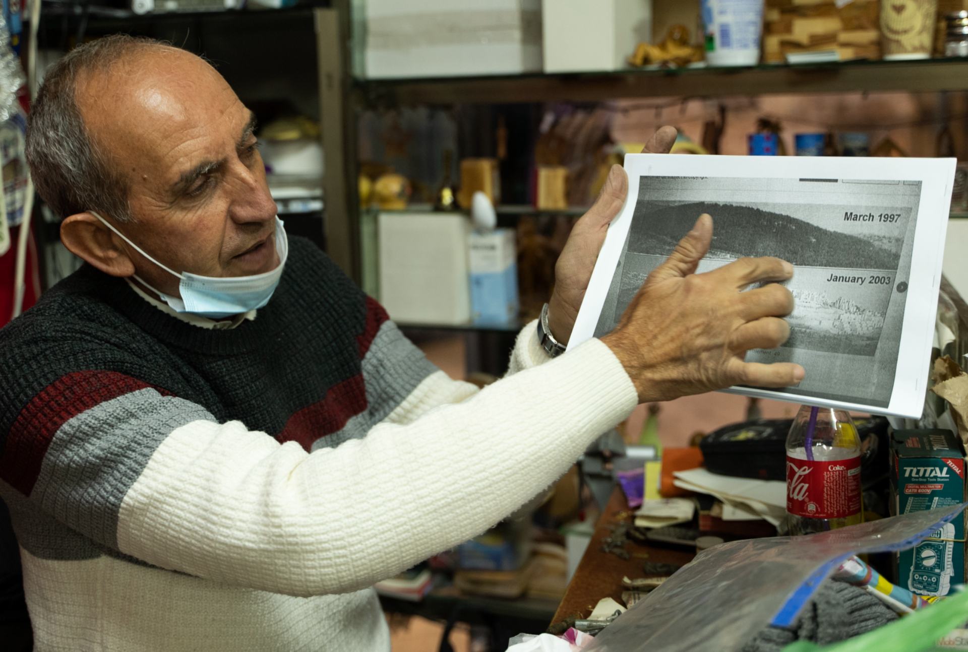 Louis Michel tient une image montrant Jabal Abu-Ghneim en 1997 et la colonie de Har Homa en 2003 (MEE/Akram Alwara)