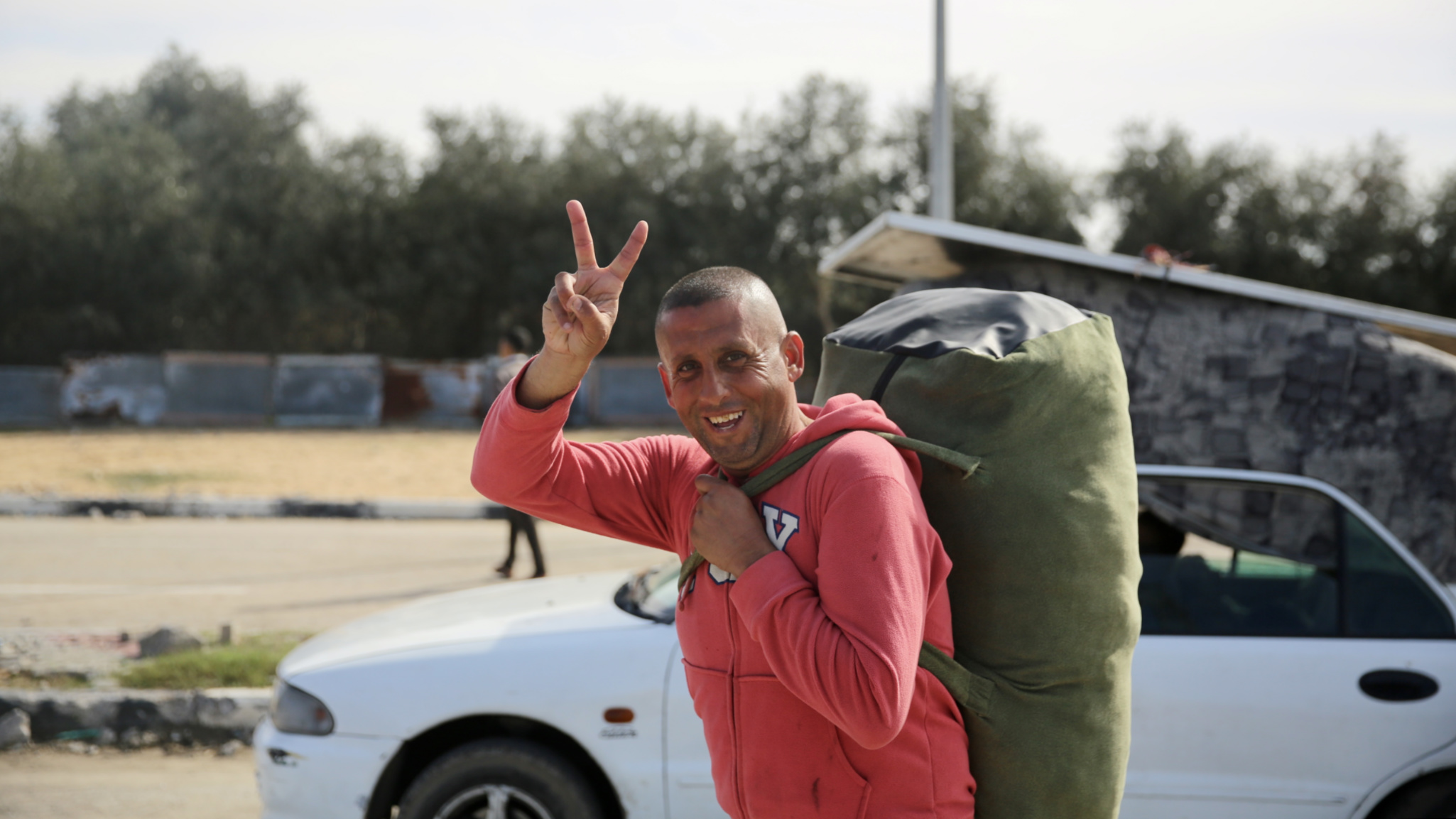 A man makes the victory sign as he waits to return to north Gaza from the Netzarim corridor on 25 January 2025 (Mohammed al-Hajjar/MEE)